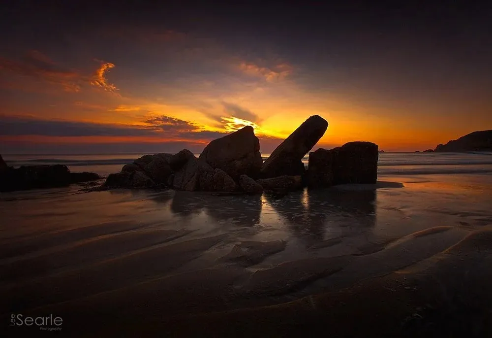 Rusting shipwreck remains on a Cornish beach at sunset, long exposure by Lee Searle