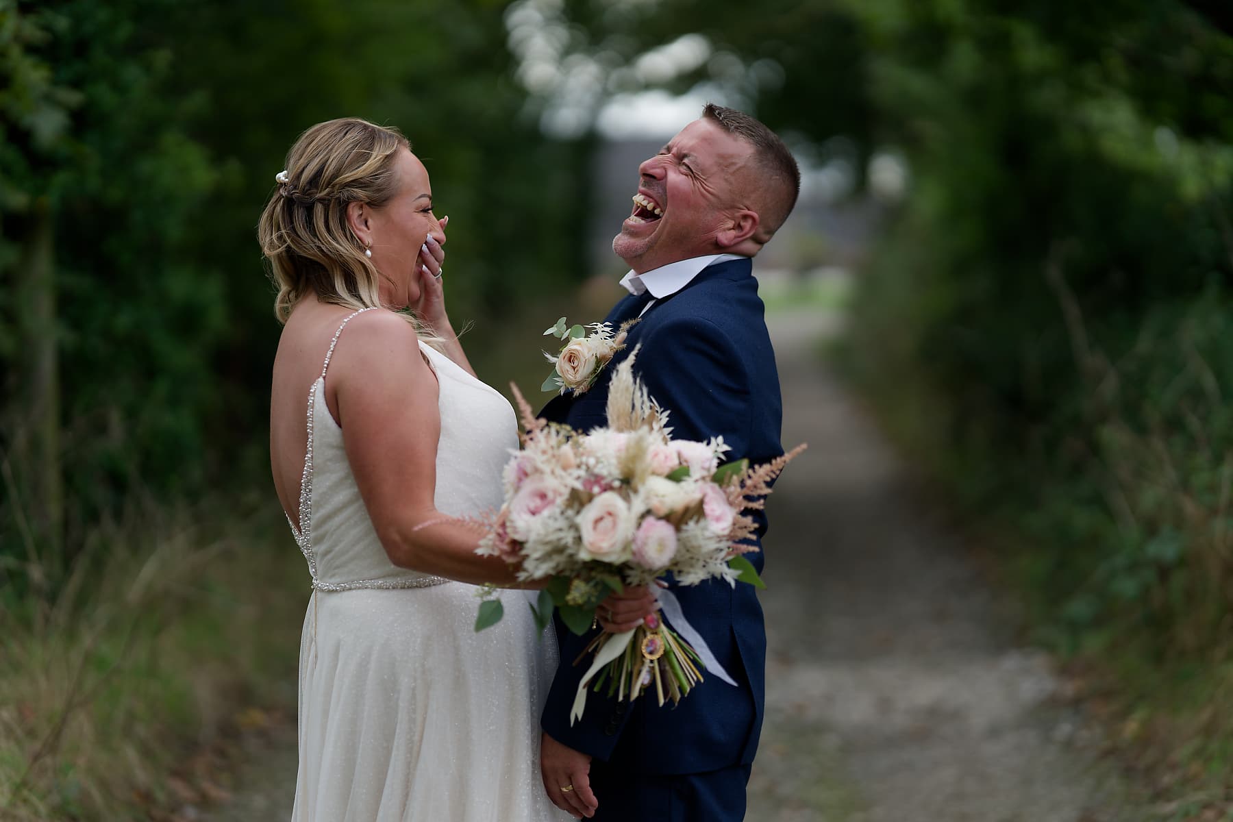 Bride and groom laughing together on a Cornish country lane