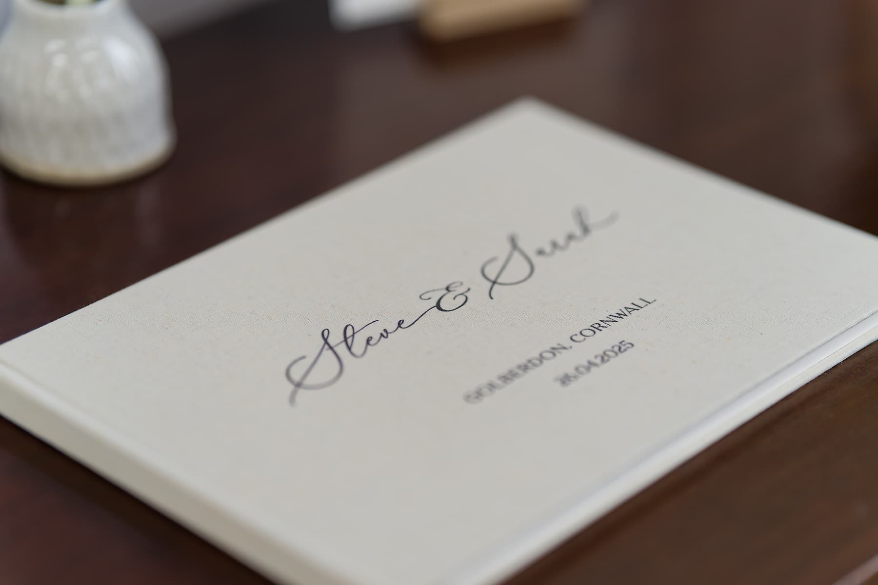 Personalised wedding album resting on a wooden table after a Cornwall celebration
