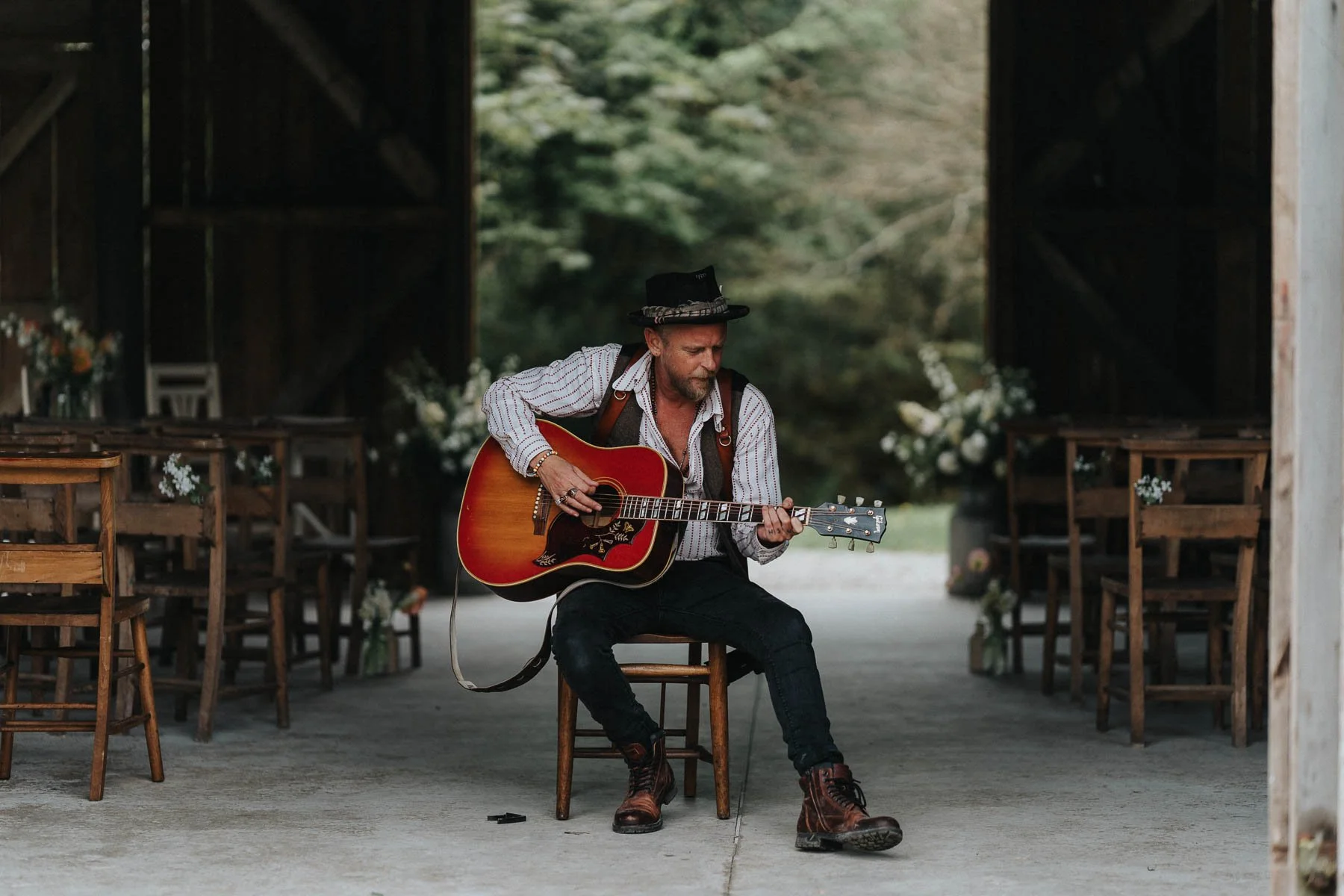 Cornwall wedding photographer Lee Searle playing guitar in a barn before a wedding