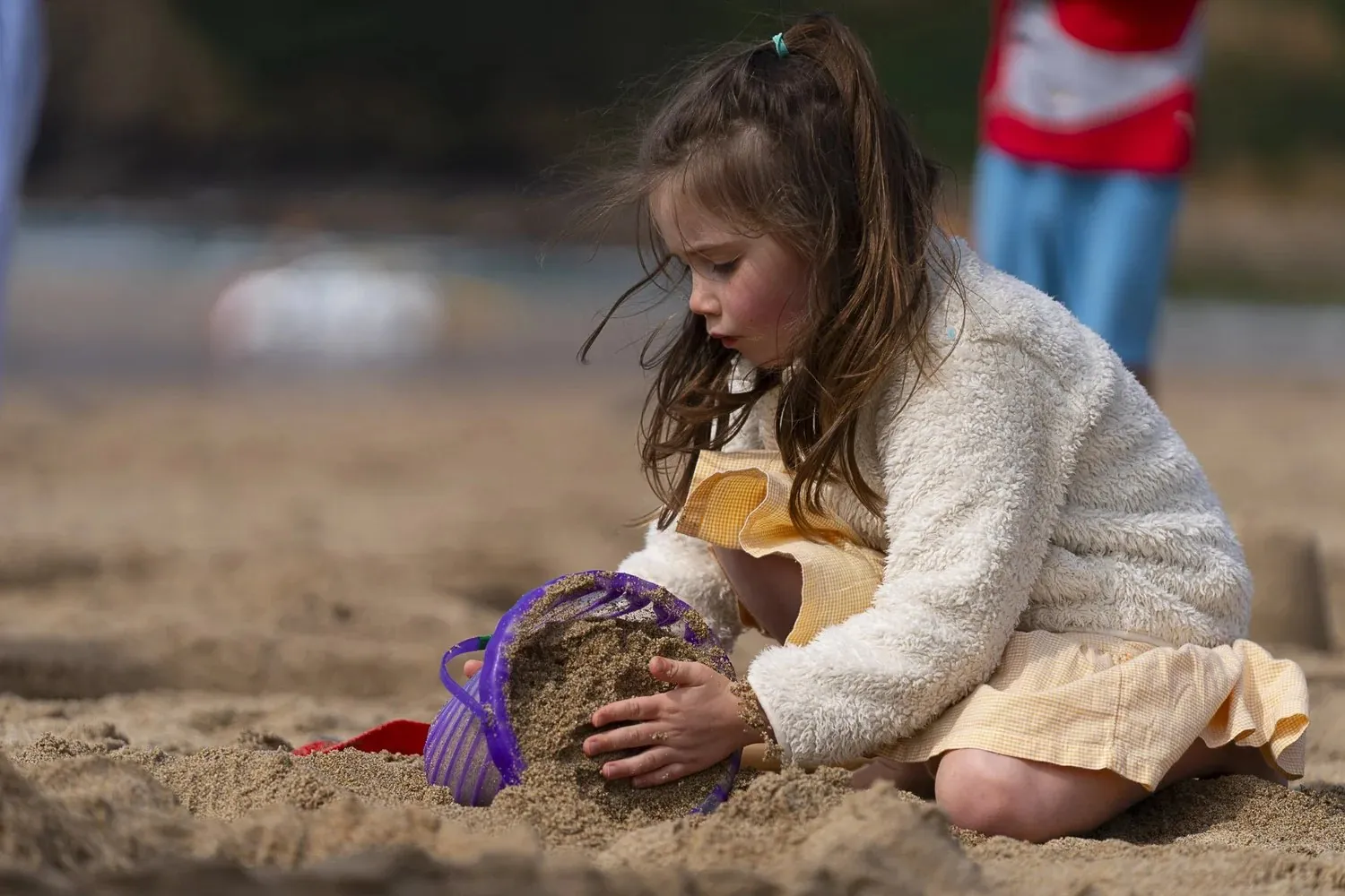 Young girl building a sandcastle on a west Cornwall beach, photographed without posing by Lee Searle