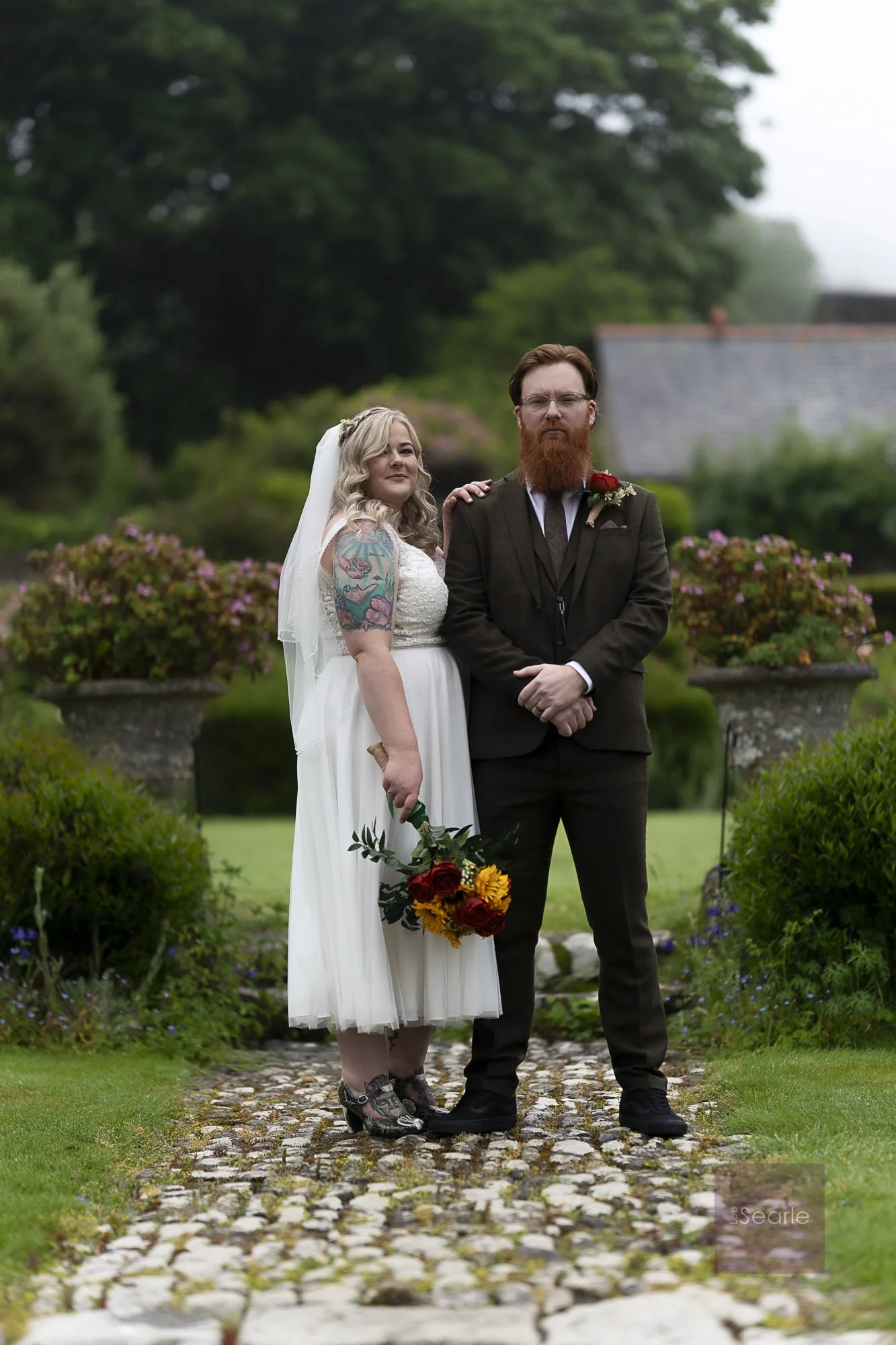 Newlyweds on the cobbled garden path at Pengersick Castle